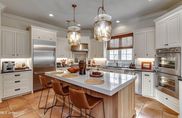 kitchen with white cabinetry, stainless steel appliances, decorative backsplash, hanging light fixtures, and a center island