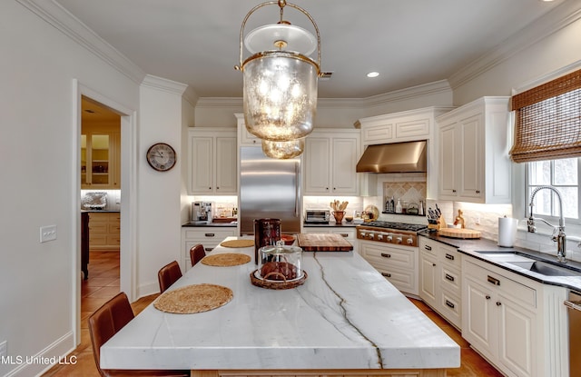 kitchen with white cabinetry, appliances with stainless steel finishes, hanging light fixtures, a kitchen island, and sink