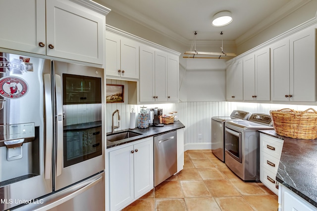 kitchen featuring appliances with stainless steel finishes, white cabinetry, sink, ornamental molding, and independent washer and dryer