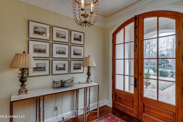 entrance foyer with french doors, dark hardwood / wood-style flooring, crown molding, and a chandelier