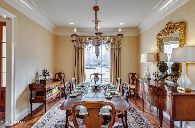 dining room with wood-type flooring, ornamental molding, and an inviting chandelier