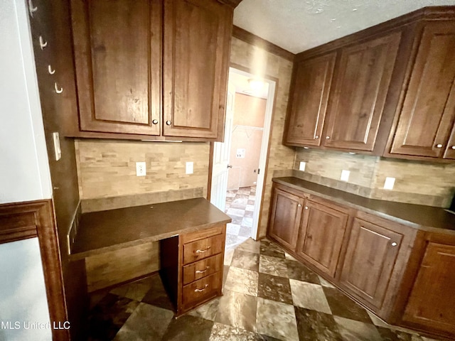 kitchen featuring dark countertops, brown cabinets, and decorative backsplash