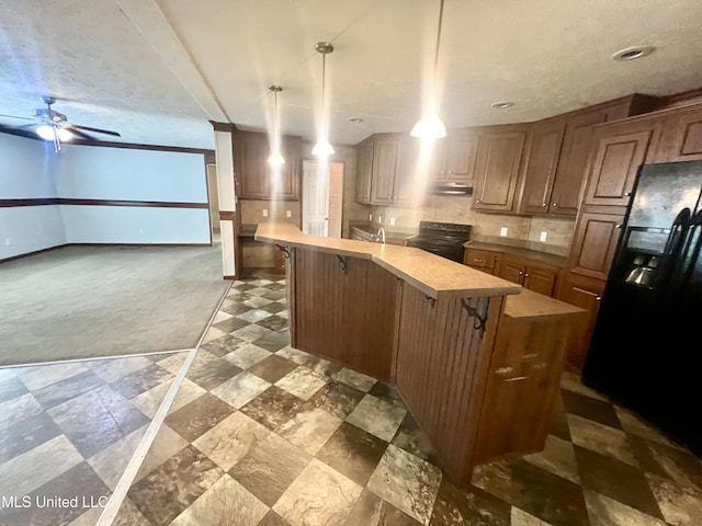 kitchen featuring black appliances, a breakfast bar, light countertops, and under cabinet range hood