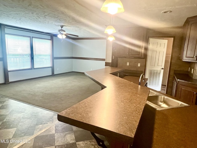 kitchen with carpet flooring, a sink, visible vents, pendant lighting, and a ceiling fan