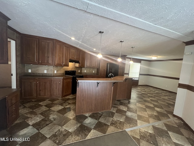 kitchen with under cabinet range hood, black appliances, a breakfast bar, baseboards, and an island with sink