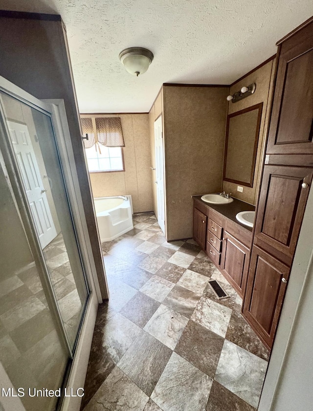 full bath with a textured ceiling, a shower stall, a sink, double vanity, and a bath