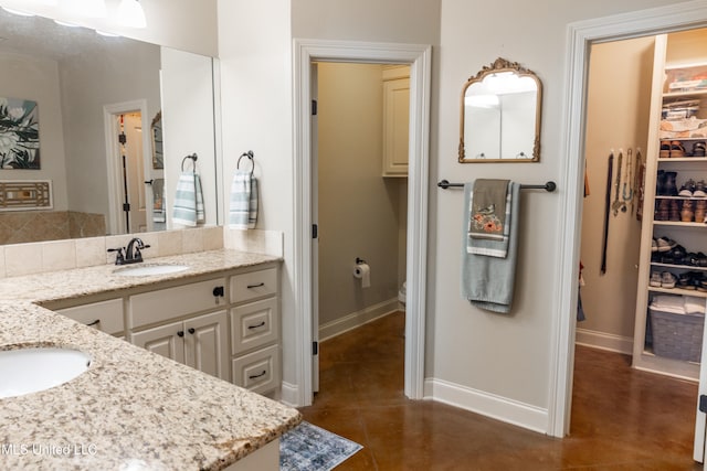 bathroom featuring a walk in closet, baseboards, vanity, and decorative backsplash