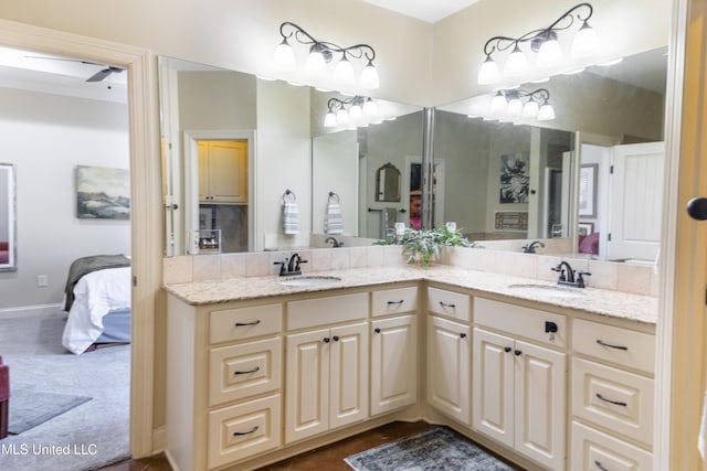 ensuite bathroom with double vanity, connected bathroom, and a sink