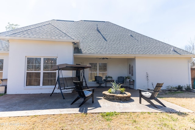 rear view of property with a patio, a fire pit, a ceiling fan, roof with shingles, and stucco siding