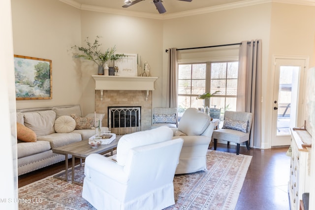 living area with ceiling fan, a fireplace, ornamental molding, and wood finished floors