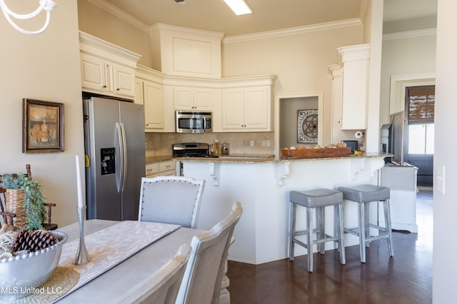 kitchen with a breakfast bar, appliances with stainless steel finishes, ornamental molding, light stone countertops, and tasteful backsplash