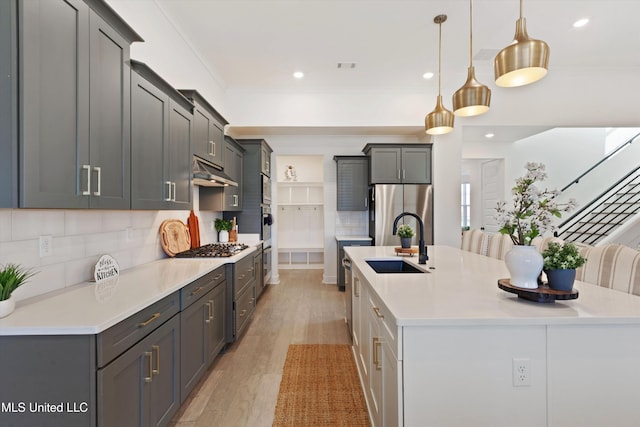 4975 Longmire Ln, Olive Branch, MS 38654 - kitchen with stainless steel appliances, a sink, under cabinet range hood, a large island, and light wood-style flooring