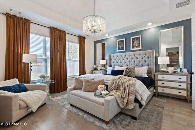 bedroom with hardwood / wood-style floors, a chandelier, crown molding, and a tray ceiling