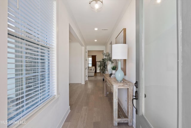 hall with wood-type flooring and crown molding