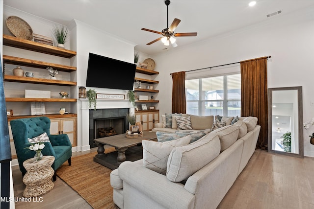 4975 Longmire Ln, Olive Branch, MS 38654 - living room featuring light wood-style floors, crown molding, a tile fireplace, and a ceiling fan