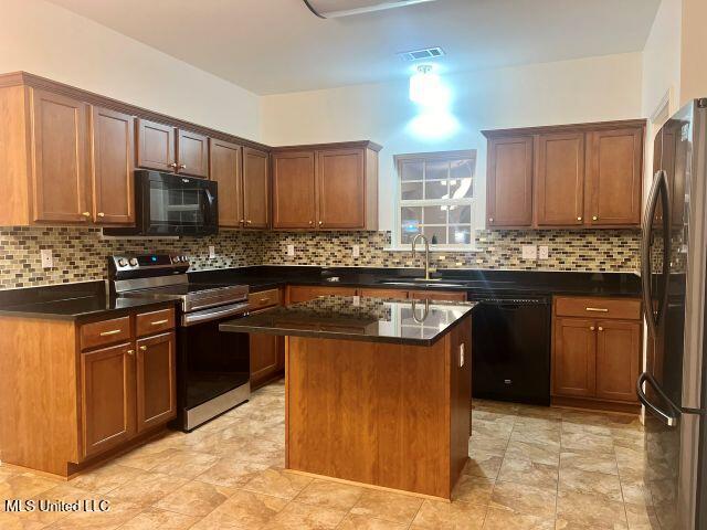 kitchen with sink, dark stone countertops, decorative backsplash, a center island, and black appliances