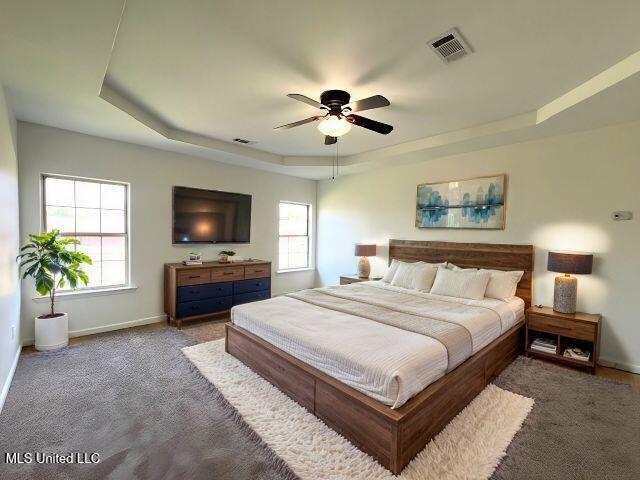 bedroom with light carpet, a tray ceiling, and ceiling fan