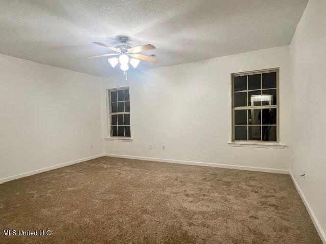 carpeted empty room featuring ceiling fan and a textured ceiling