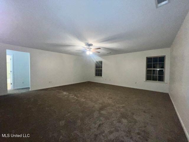 interior space with dark carpet and ceiling fan