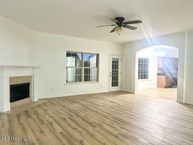 unfurnished living room with ceiling fan, a fireplace, and light hardwood / wood-style floors