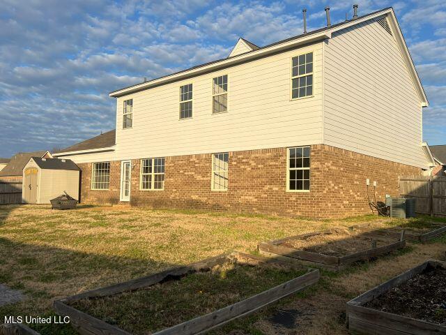 back of house featuring a yard and a storage unit