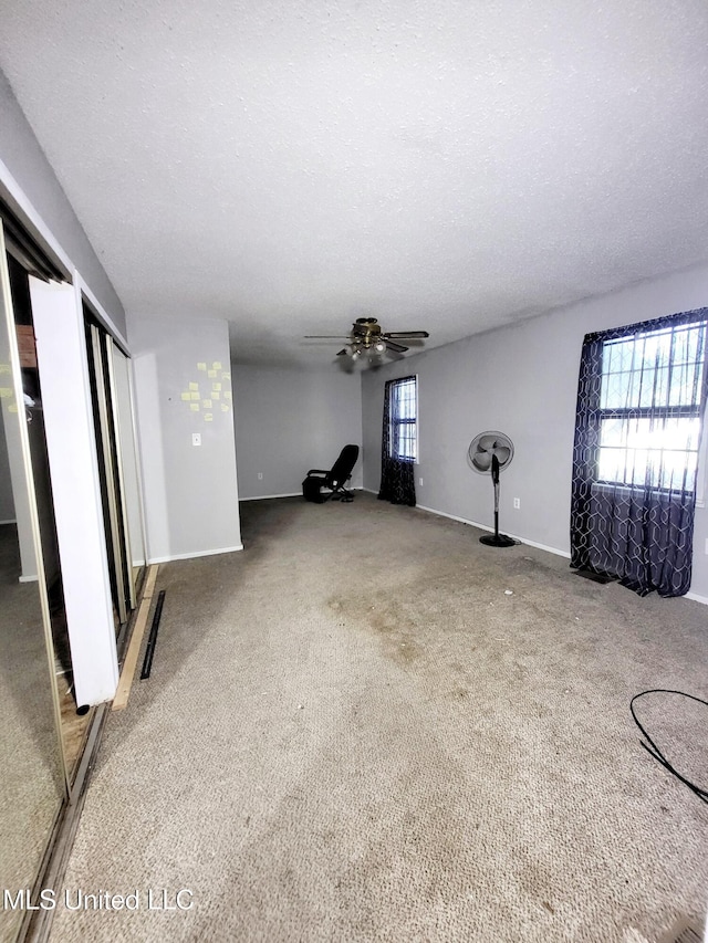 98 Danny Ln, Sardis, MS 38666 - unfurnished living room featuring baseboards, ceiling fan, carpet floors, and a textured ceiling