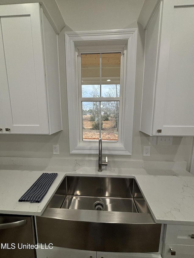 kitchen featuring sink, light stone countertops, and white cabinets