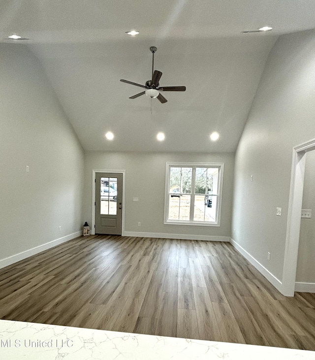 unfurnished living room featuring plenty of natural light, high vaulted ceiling, ceiling fan, and light wood-type flooring