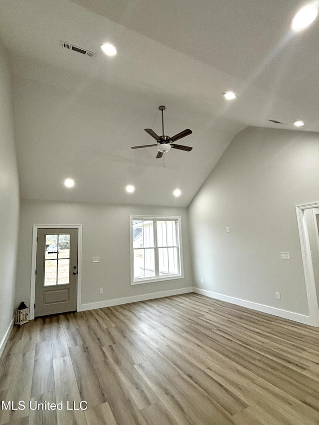 unfurnished living room featuring ceiling fan, lofted ceiling, a wealth of natural light, and light wood-type flooring