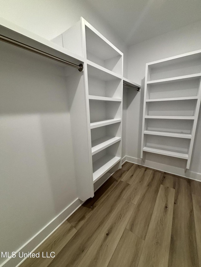 walk in closet with dark wood-type flooring