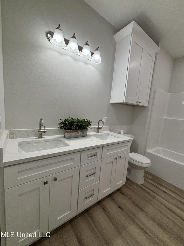 full bathroom with vanity, hardwood / wood-style flooring,  shower combination, and toilet