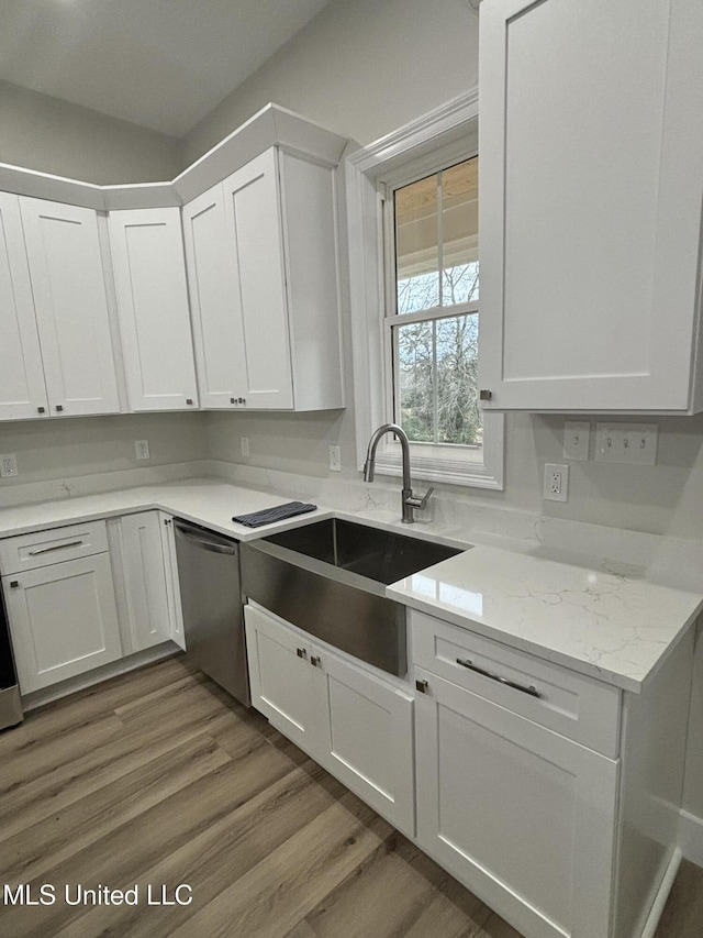 kitchen with stainless steel dishwasher, light stone countertops, sink, and white cabinets