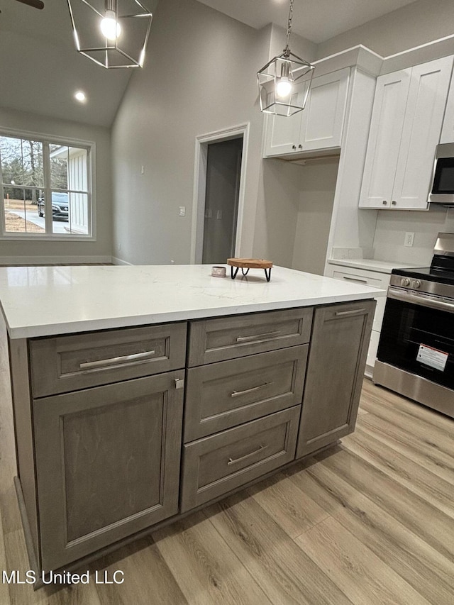 kitchen with white cabinetry, stainless steel appliances, decorative light fixtures, and light hardwood / wood-style flooring