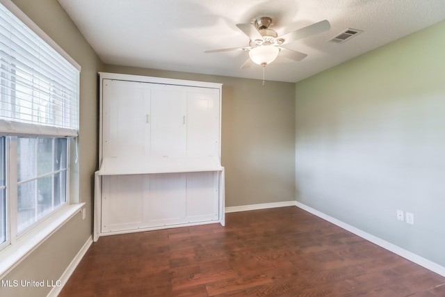 unfurnished bedroom with wood finished floors, visible vents, baseboards, and multiple windows