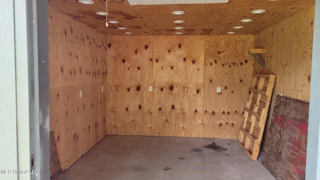 spare room featuring concrete floors and wood walls