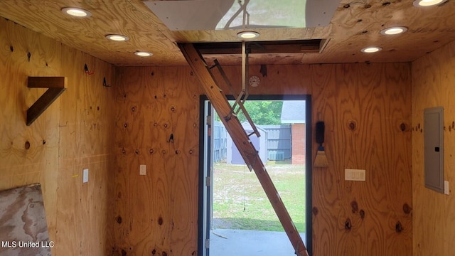 doorway to outside with electric panel and wood walls