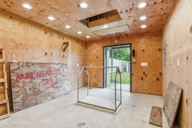 interior space with concrete floors, wood walls, and a skylight