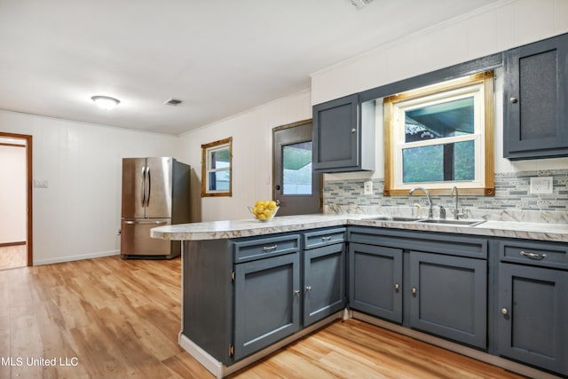 kitchen featuring gray cabinetry, sink, stainless steel fridge, and light wood-type flooring