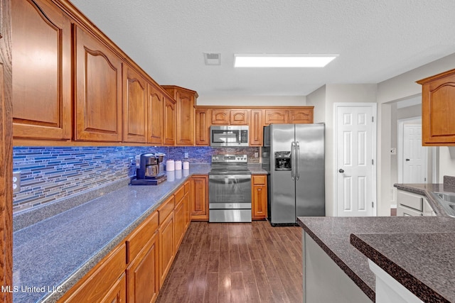 13245 Braybourne Pkwy, Olive Branch, MS 38654 - kitchen featuring stainless steel appliances, dark wood finished floors, decorative backsplash, brown cabinets, and a textured ceiling