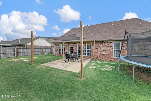 13245 Braybourne Pkwy, Olive Branch, MS 38654 - back of property featuring a trampoline, brick siding, a patio, and a shingled roof