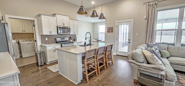 13453 Birch Bnd, Olive Branch, MS 38654 - kitchen featuring stainless steel appliances, independent washer and dryer, a sink, open floor plan, and dark wood-type flooring