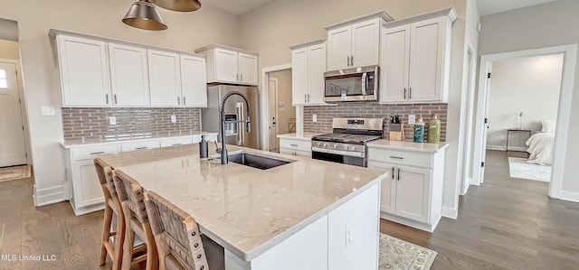 13453 Birch Bnd, Olive Branch, MS 38654 - kitchen featuring appliances with stainless steel finishes, wood finished floors, decorative backsplash, and an island with sink