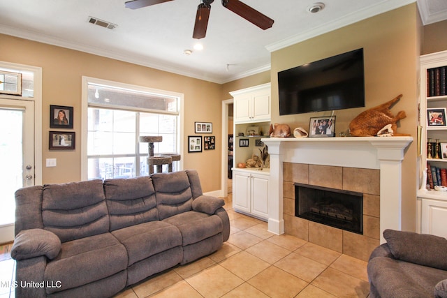 living room with a wealth of natural light, crown molding, a tile fireplace, and light tile patterned floors