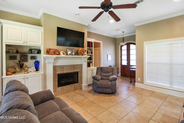 tiled living room with ceiling fan, ornamental molding, and a tile fireplace