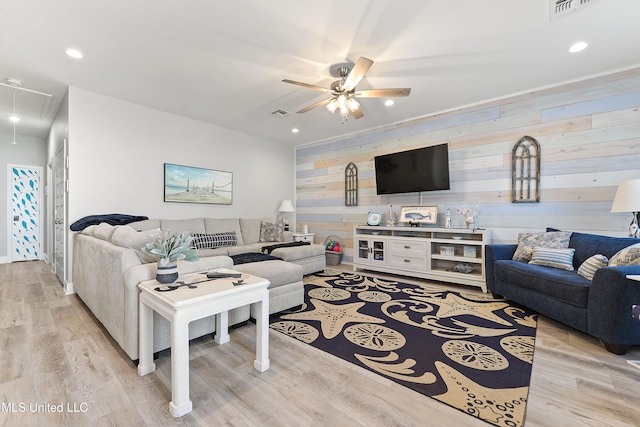 living room with wooden walls, light hardwood / wood-style flooring, and ceiling fan