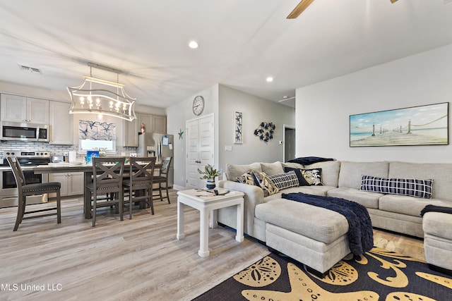 living room with light hardwood / wood-style floors and an inviting chandelier