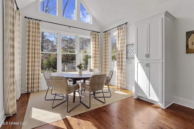 dining space featuring baseboards, dark wood-style flooring, and high vaulted ceiling