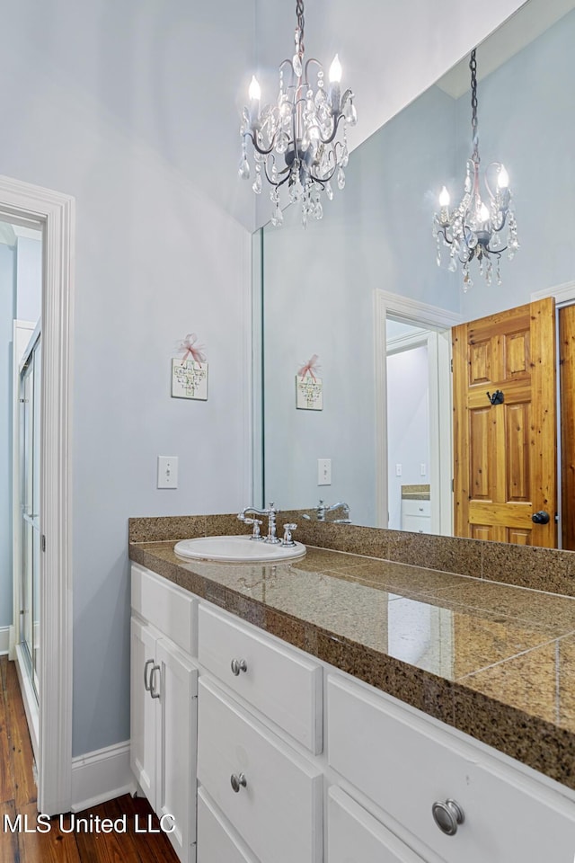 bathroom featuring vanity, a notable chandelier, wood finished floors, and baseboards