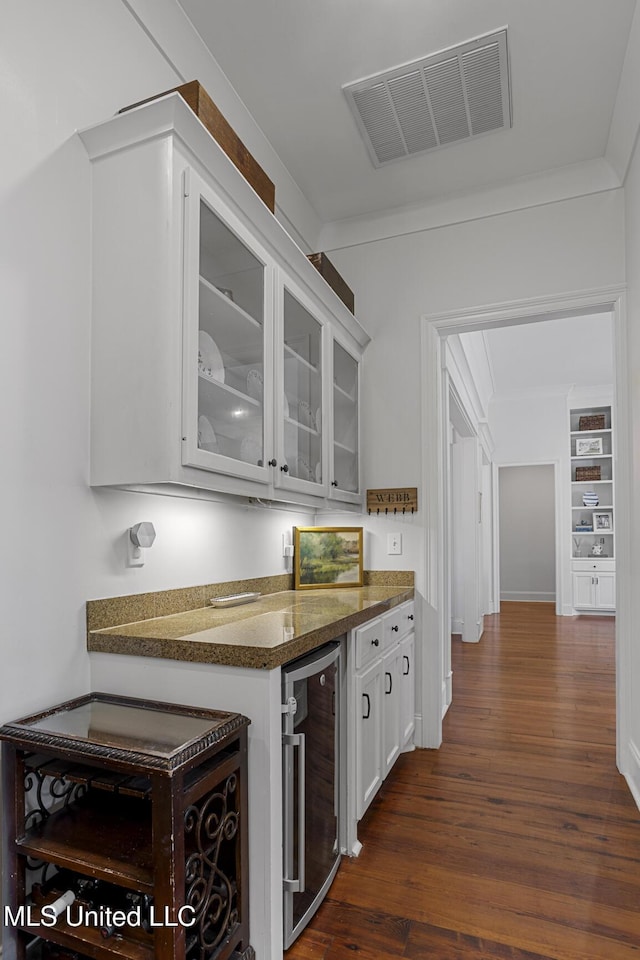 bar featuring dark wood-type flooring, wine cooler, visible vents, and ornamental molding