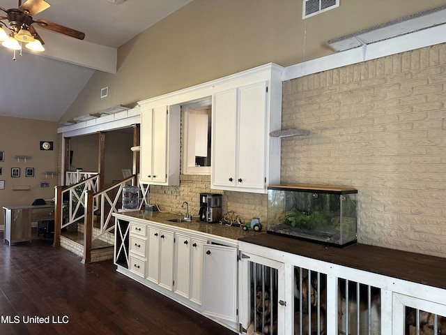 kitchen featuring decorative backsplash, lofted ceiling with beams, and white cabinetry